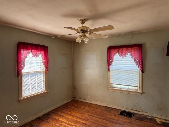 unfurnished room featuring healthy amount of natural light, wood finished floors, ceiling fan, and baseboards