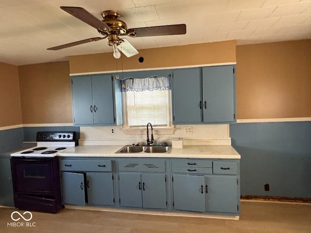 kitchen featuring range with electric stovetop, a sink, a ceiling fan, light countertops, and gray cabinetry