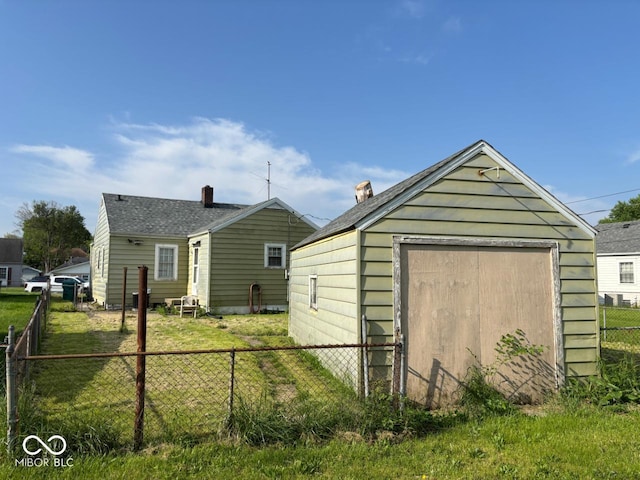 back of property with fence, a storage unit, and an outbuilding