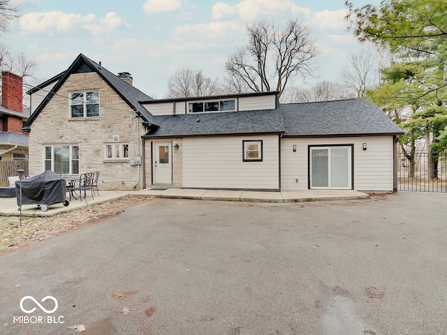 3659 Watson Rd, Indianapolis, IN 46205 - back of property with a patio, roof with shingles, a chimney, fence, and stone siding
