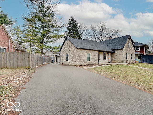 3659 Watson Rd, Indianapolis, IN 46205 - view of front of home featuring stone siding, a gate, driveway, and a chimney