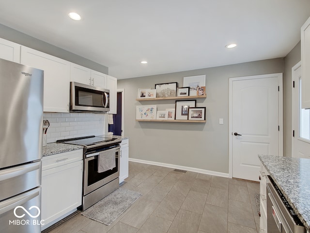 3659 Watson Rd, Indianapolis, IN 46205 - kitchen featuring stainless steel appliances, backsplash, white cabinetry, light stone countertops, and baseboards