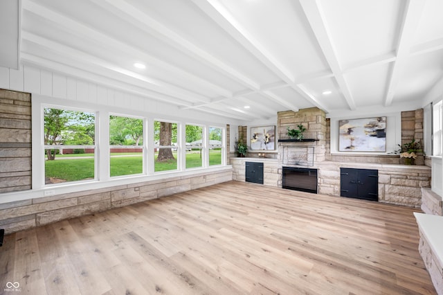 unfurnished sunroom with wood finished floors, beam ceiling, healthy amount of natural light, and a wooden deck
