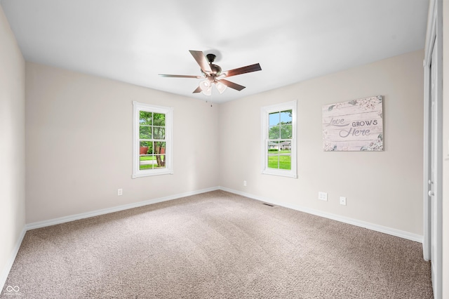 carpeted spare room with ceiling fan and baseboards