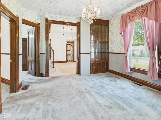 814 Walnut St, Anderson, IN 46012 - carpeted empty room featuring a chandelier, wallpapered walls, plenty of natural light, stairway, and baseboards
