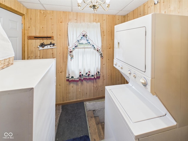 814 Walnut St, Anderson, IN 46012 - laundry area with stacked washer / drying machine, wooden walls, and a chandelier