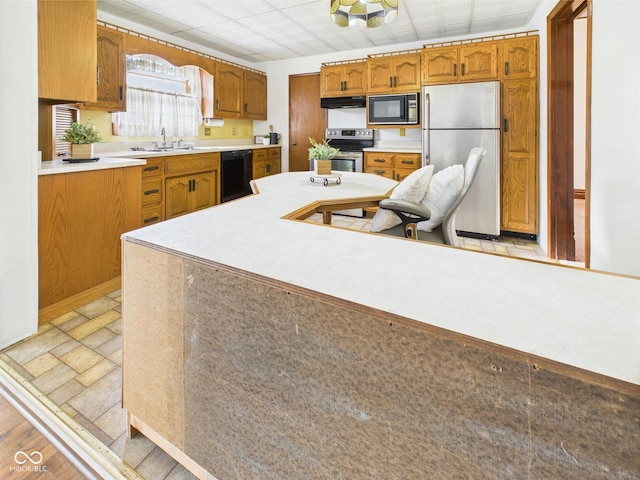 814 Walnut St, Anderson, IN 46012 - kitchen featuring black appliances, light countertops, brown cabinetry, and a sink