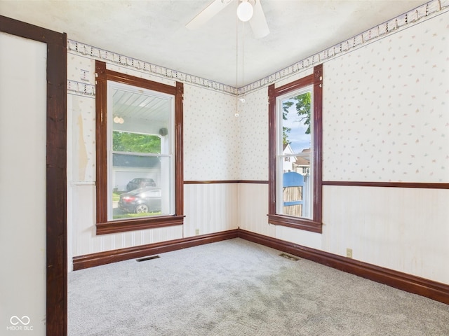 814 Walnut St, Anderson, IN 46012 - spare room featuring wallpapered walls, carpet, a ceiling fan, baseboards, and a wainscoted wall