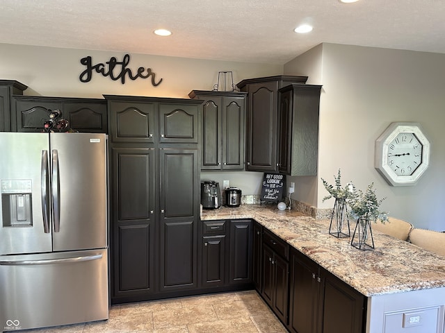 kitchen with stainless steel fridge with ice dispenser, a peninsula, light stone counters, and recessed lighting