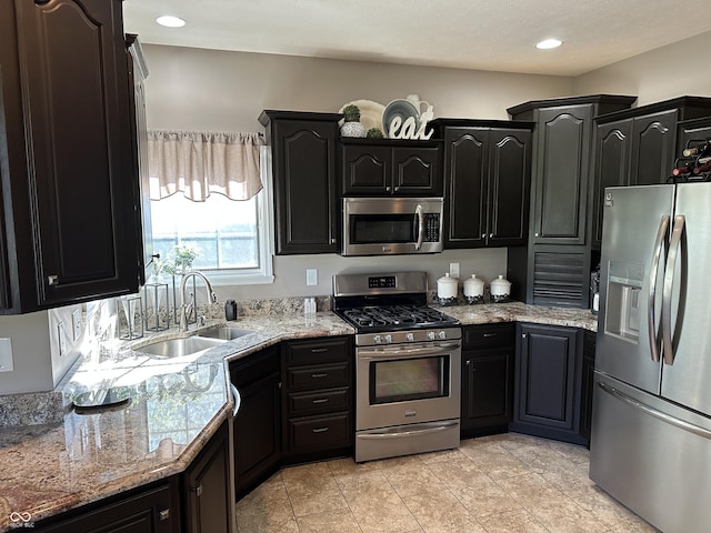 kitchen with stainless steel appliances, a sink, and dark cabinets