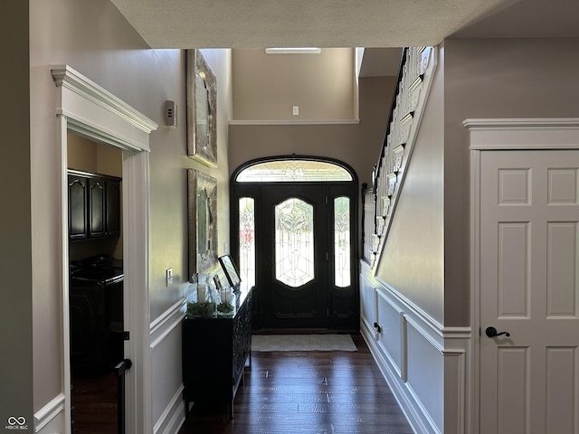 foyer featuring a decorative wall, dark wood finished floors, a wainscoted wall, and washing machine and dryer