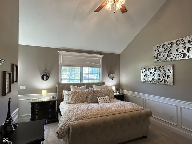 bedroom featuring a decorative wall, a wainscoted wall, a ceiling fan, and lofted ceiling