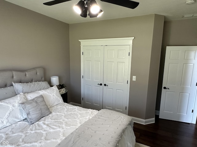 bedroom with dark wood-type flooring, a closet, baseboards, and a ceiling fan
