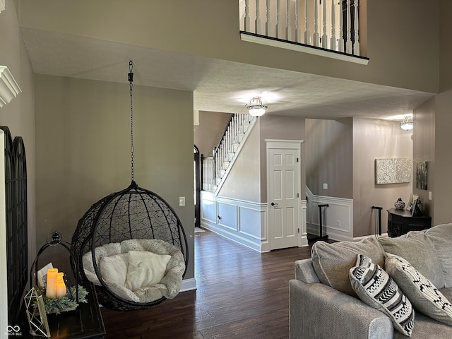 living room featuring wood finished floors, stairs, and a wainscoted wall