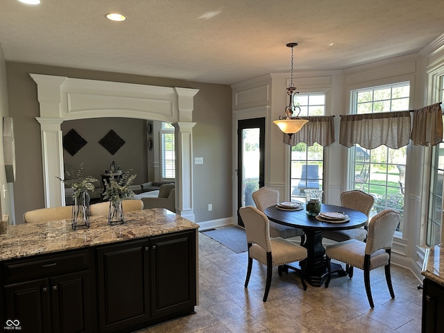 dining space featuring plenty of natural light, ornate columns, baseboards, recessed lighting, and light stone finish floors