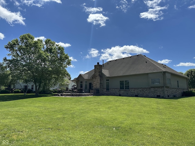 back of house featuring a chimney, a lawn, a patio area, and brick siding