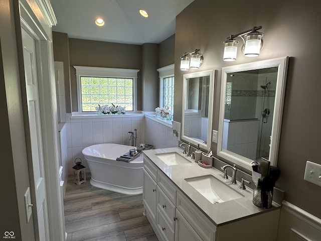 bathroom featuring wainscoting, a freestanding bath, recessed lighting, wood finished floors, and vaulted ceiling