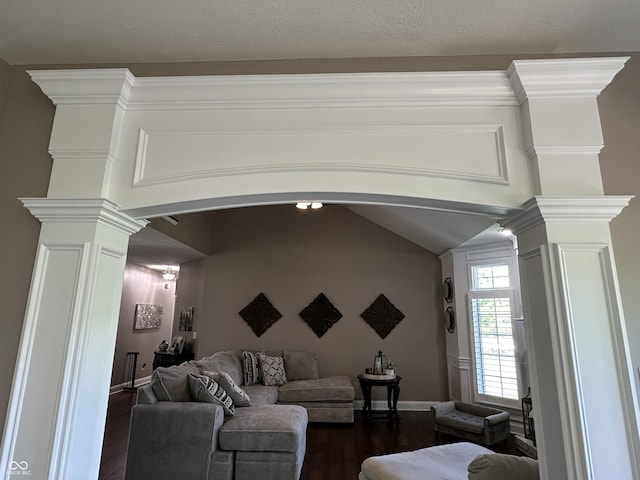 living area featuring decorative columns, arched walkways, dark wood-style flooring, baseboards, and vaulted ceiling