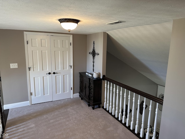 hallway featuring a textured ceiling, carpet, and baseboards