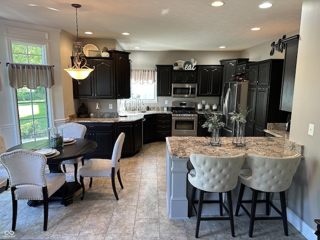 kitchen featuring stainless steel appliances, a peninsula, plenty of natural light, a kitchen breakfast bar, and recessed lighting