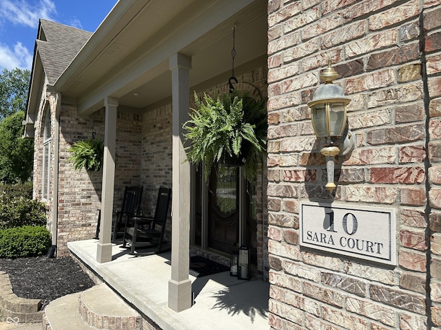 entrance to property with brick siding and a shingled roof