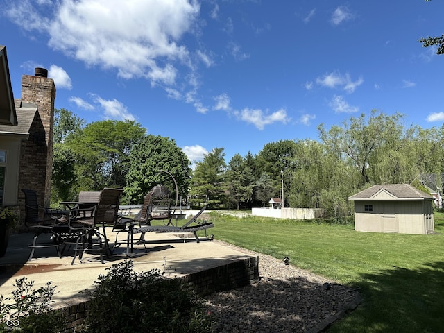 view of green lawn with a patio and view of wooded area