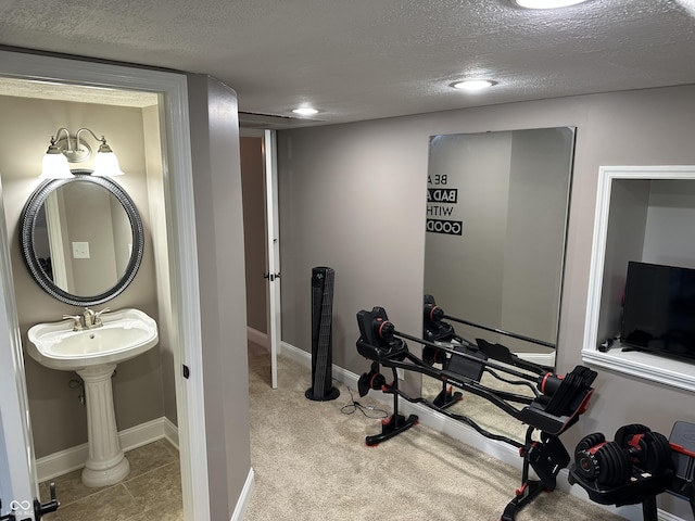 exercise area featuring a textured ceiling, recessed lighting, baseboards, carpet flooring, and a sink
