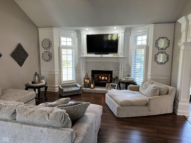 living room featuring a brick fireplace, lofted ceiling, wood finished floors, a wainscoted wall, and a decorative wall