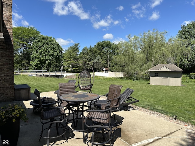 view of patio / terrace featuring an outbuilding, view of wooded area, and outdoor dining space