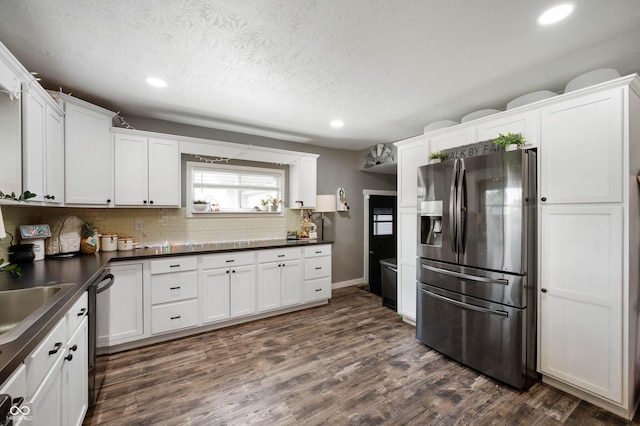 kitchen featuring stainless steel refrigerator with ice dispenser, recessed lighting, dark wood-style flooring, tasteful backsplash, and dark countertops