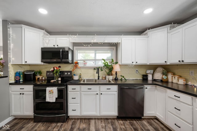 kitchen featuring appliances with stainless steel finishes, a sink, dark countertops, white cabinetry, and recessed lighting