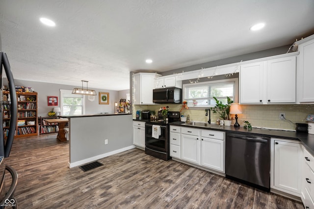 kitchen featuring range with two ovens, stainless steel dishwasher, a sink, dark countertops, and a peninsula