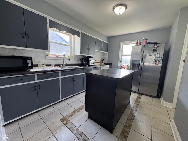 144 S 7th Ave, Beech Grove, IN 46107 - kitchen featuring stainless steel fridge with ice dispenser, black microwave, a sink, light tile patterned floors, and plenty of natural light