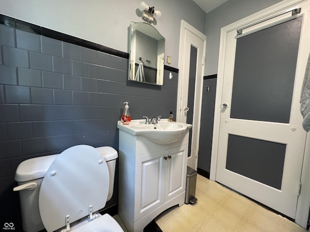 144 S 7th Ave, Beech Grove, IN 46107 - bathroom featuring toilet, tile patterned floors, vanity, tile walls, and a wainscoted wall