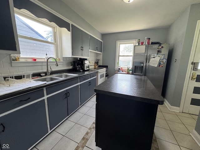144 S 7th Ave, Beech Grove, IN 46107 - kitchen featuring white electric stove, dark countertops, a sink, light tile patterned floors, and stainless steel fridge