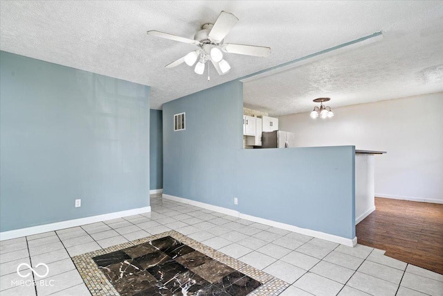 1170 N Concord St, Indianapolis, IN 46222 - unfurnished room featuring light tile patterned floors, a textured ceiling, a chandelier, a ceiling fan, and baseboards