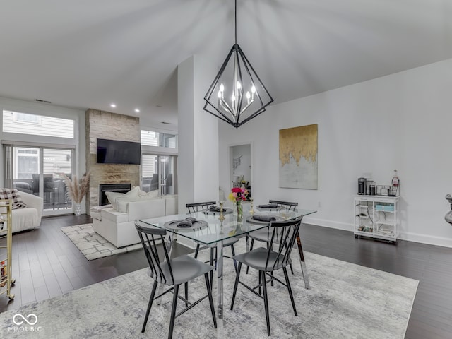 222 N E St Unit 103, Indianapolis, IN 46204 - dining room with dark wood-type flooring, a stone fireplace, a chandelier, baseboards, and a high ceiling