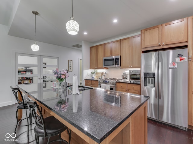 222 N E St Unit 103, Indianapolis, IN 46204 - kitchen featuring stainless steel appliances, dark wood-type flooring, a center island with sink, tasteful backsplash, and a kitchen breakfast bar
