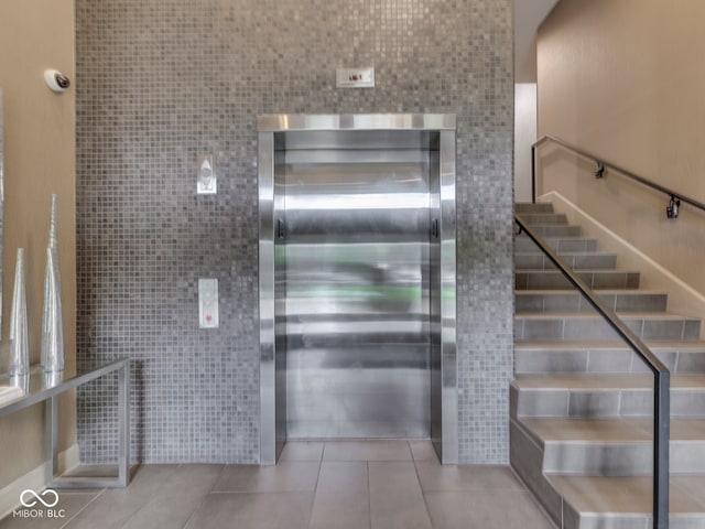 222 N E St Unit 103, Indianapolis, IN 46204 - staircase featuring tile walls, elevator, and tile patterned flooring
