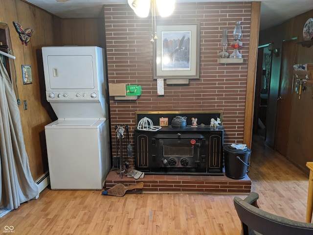 7114 Locust Lake W Dr, Spencer, IN 47460 - clothes washing area with stacked washing machine and dryer, wood finished floors, a baseboard radiator, and wooden walls