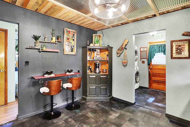 bar featuring stacked washing machine and dryer, tile patterned floors, and baseboards