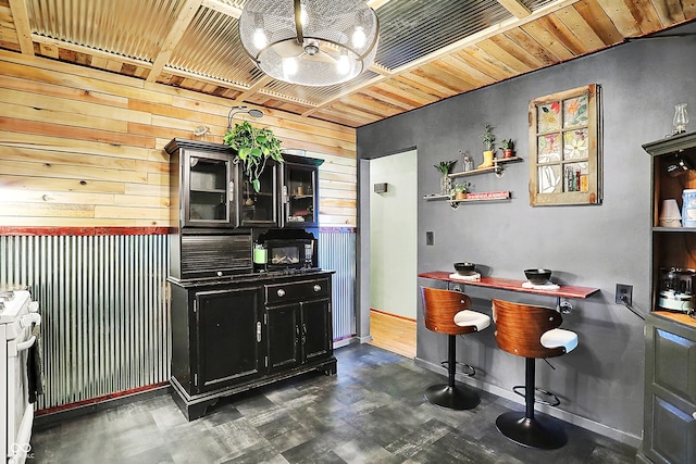 bar area with wood walls, white range, black microwave, a chandelier, and dark floors