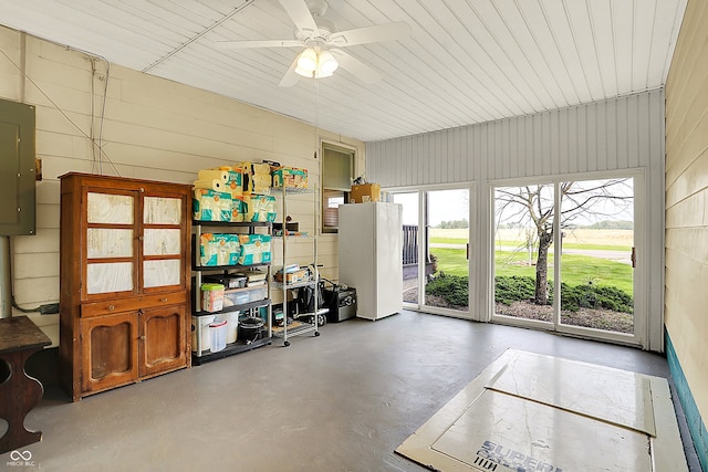 dining area featuring concrete flooring, ceiling fan, and wood walls