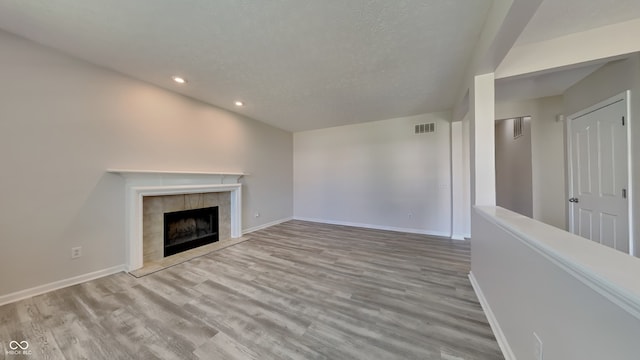 12878 Ari Ln, Fishers, IN 46037 - unfurnished living room with recessed lighting, wood finished floors, baseboards, a tile fireplace, and a textured ceiling