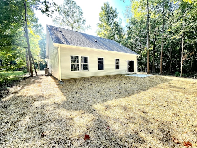 rear view of property featuring a shingled roof, a patio, and cooling unit