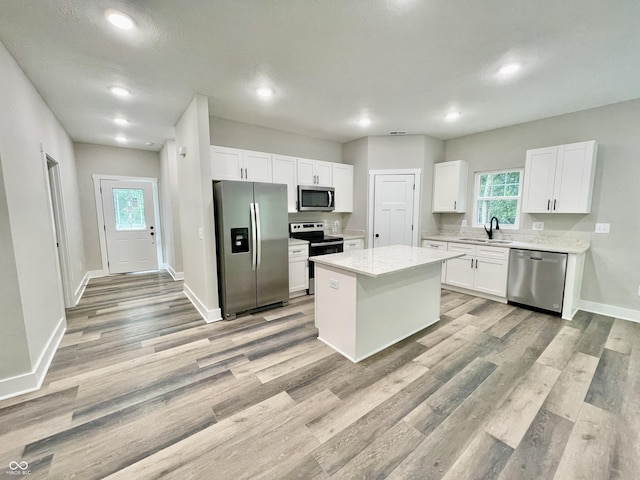 kitchen with appliances with stainless steel finishes, a sink, white cabinetry, light wood-style flooring, and recessed lighting
