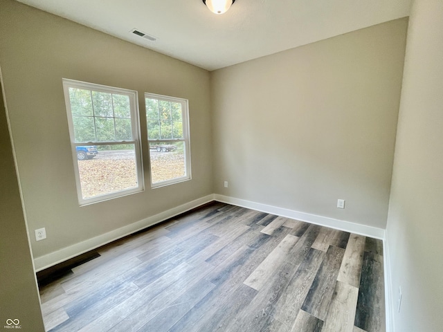 spare room featuring dark wood-style flooring and baseboards