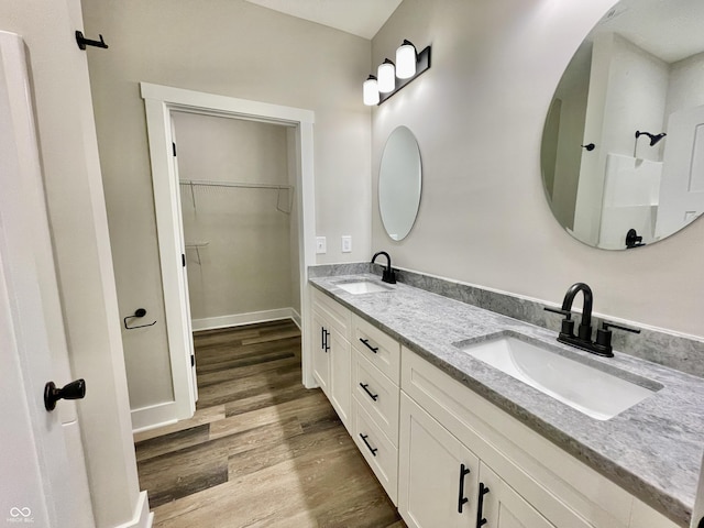 full bathroom featuring wood finished floors, double vanity, and a spacious closet