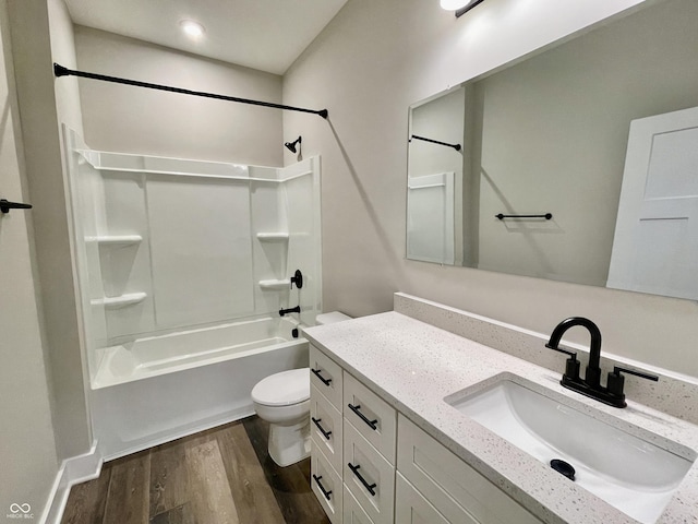 bathroom with toilet, wood finished floors,  shower combination, and vanity