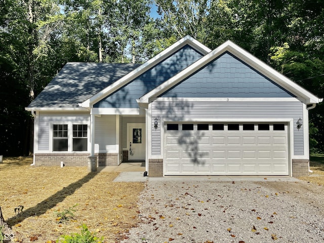 craftsman house featuring an attached garage, gravel driveway, and brick siding